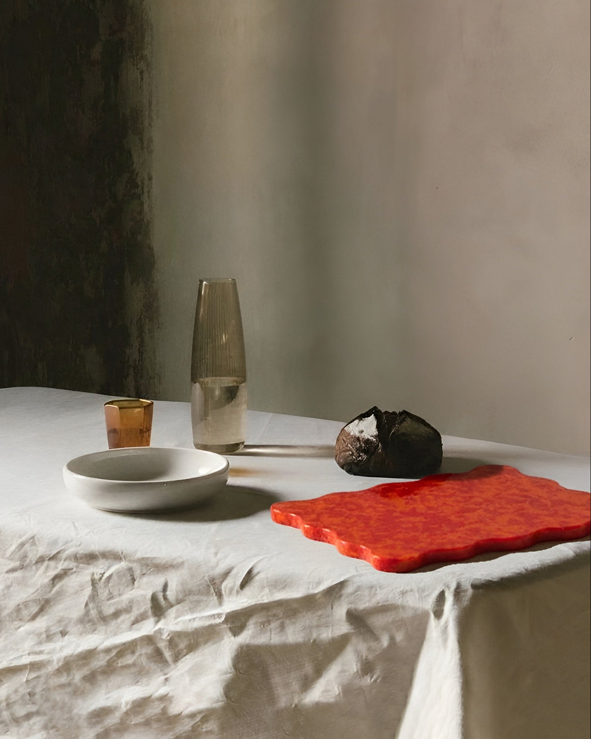 Table setting with a bowl, glass, and dessert on a white tablecloth.
